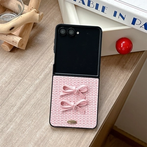 Detailed view of pink woven texture case with satin bows and gold plaque for flip phones