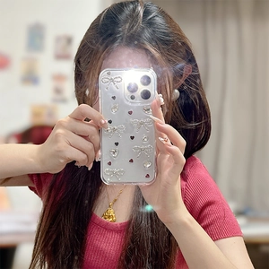 Détail de la coque iPhone transparente avec nœuds strass 3D et motifs cœurs en main