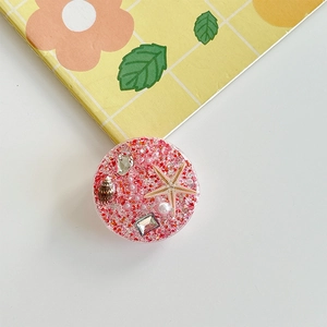 Detailed macro of ocean-themed phone grip with starfish shell glitter and pearls