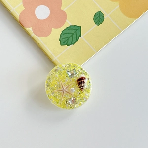 Macro shot of yellow resin phone socket featuring real starfish, shells and gold sequins