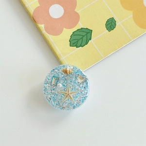 Macro view of ocean starfish resin phone grip with blue glitter sequins and sea shells
