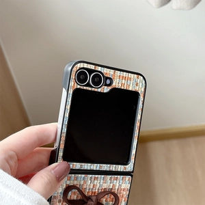 Close-up of woven tweed fabric texture and 3D bow detail on a folding phone case