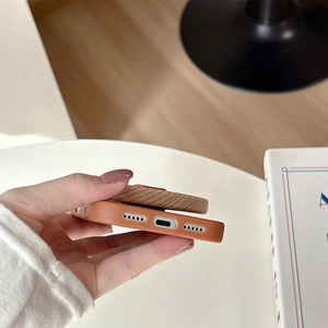 Close-up of brown leather phone case with precise bottom cutouts and wood magnet