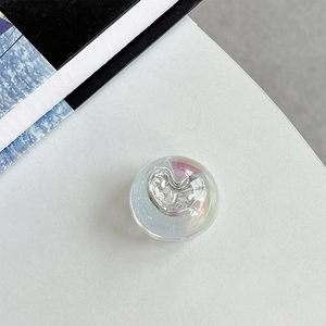 Detail of a transparent iridescent bubble phone socket featuring a silver fluid heart center