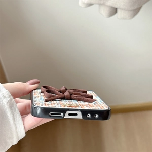 Macro detail of woven fabric phone case featuring an elegant brown ribbon bow decoration
