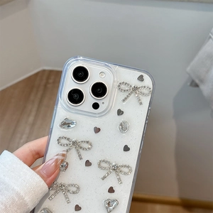 Détail de coque iPhone pailletée avec nœuds en strass 3D et décorations en perles