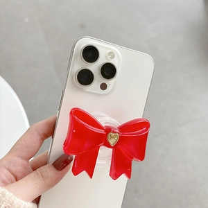Red bowknot phone socket stand with golden heart detail on a white smartphone