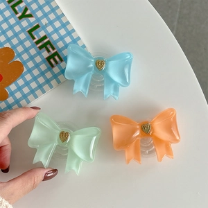 Close-up of three jelly-texture bow phone grips in blue, green, and orange colors