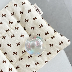 Detail of cream cushion with brown bow patterns and an iridescent crystal sphere accessory