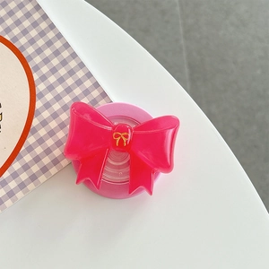 Nahaufnahme der rosa Schleife Handyhalterung mit Goldakzent auf lila Karomuster