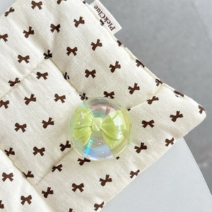 Detail of iridescent crystal ball phone grip with a green bow embedded inside the globe