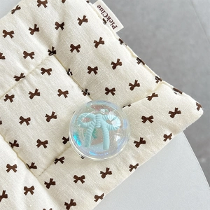 Close-up of beige fabric pad with brown bows and blue bow crystal ball phone grip