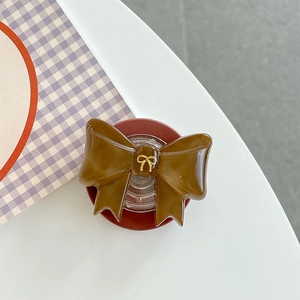 Detailansicht eines braunen Harz-Griptoks mit goldener 3D-Schleife und roter Basis