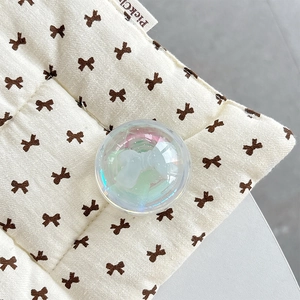 Close-up of iridescent crystal ball phone grip with 3D white bow on quilted fabric