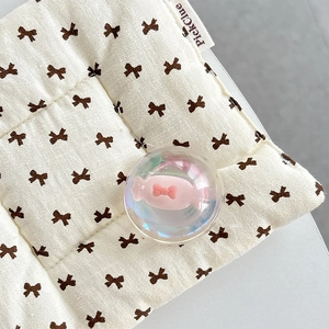 Close-up of a clear crystal ball with a pink bow candy charm on a knit cushion