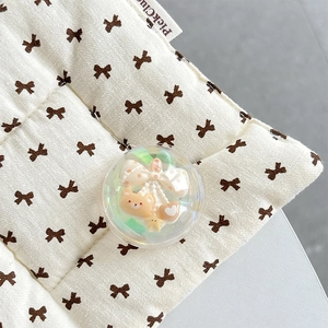 Macro view of cute crystal ball phone grip with brown bear and bow on quilted base