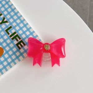 Detailed macro view of the glossy pink resin bow phone stand with a golden heart center