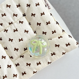 Close-up of a transparent resin ball phone grip with a green bow inside on a soft mat
