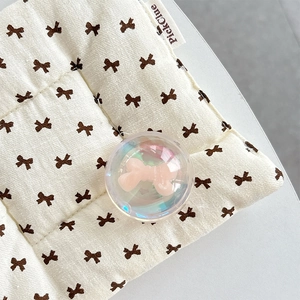 Close-up of a holographic crystal ball phone grip with pink bow inside on quilted fabric