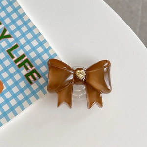 Macro detail of brown bow phone grip with vintage gold heart relief on white desk