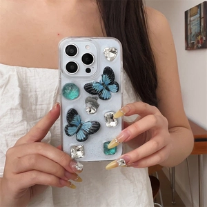 Close-up of glitter phone case with 3D blue butterflies and sparkling faux gemstones