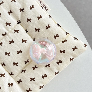 Close-up of a pink bow inside a glittery crystal ball phone grip on a quilted fabric