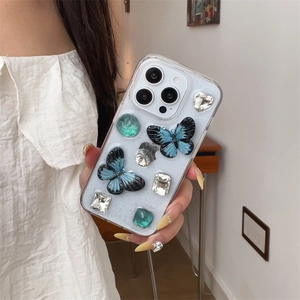 Clear iPhone case featuring 3D blue gradient butterflies and sparkling crystal rhinestones