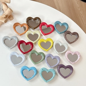 Collage of heart-shaped phone grip mirrors with artistic ink splatter patterns in various colors