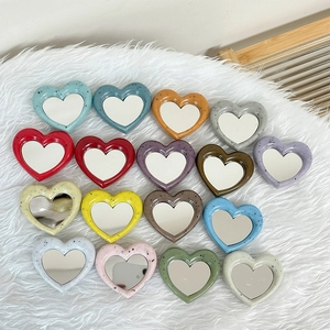 Colorful heart-shaped mirror phone grips with terrazzo texture on a plush white background