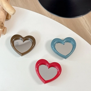 Close-up of heart-shaped phone mirror brackets in brown, blue, and red resin frames