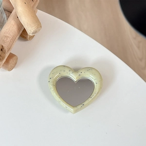 Detail of cream heart phone grip with speckled stone texture and functional mirror surface