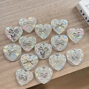 Detailed view of iridescent heart-shaped phone grips with silver bow and rhinestone accents