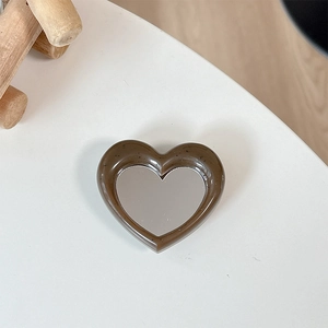 Detail of heart-shaped phone grip with brown frame and integrated makeup mirror