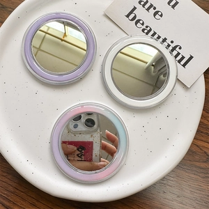 Close-up of three round MagSafe makeup mirrors in purple, white, and blue pastel tones