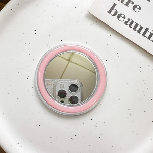 Detail view of a round MagSafe vanity mirror with a pink inner ring and transparent base