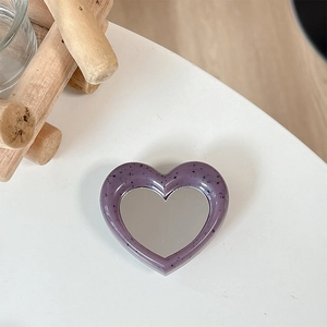Close-up of heart-shaped phone grip with purple speckled frame and makeup mirror