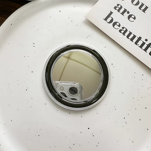 Detail of round Magsafe phone grip with a built-in makeup mirror on a white tray