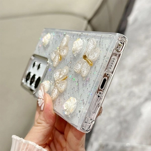 Macro detail of clear phone case featuring 3D white flowers and sparkling butterfly glitter