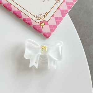 Detailed view of a white translucent bow-shaped phone grip with a gold butterfly accent