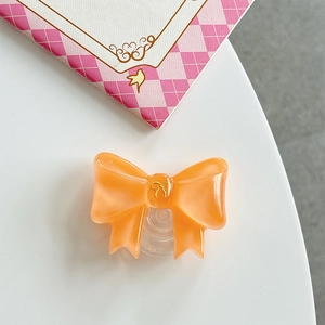 Detail of a bright orange bow phone grip with a gold emblem on a white background
