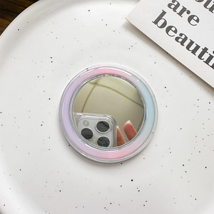 Detail shot of a round MagSafe mirror base with pink to blue gradient border on a tray