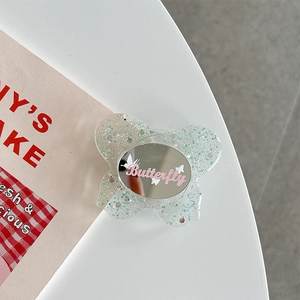 Detail of butterfly phone grip with silver glitter resin and small circular makeup mirror