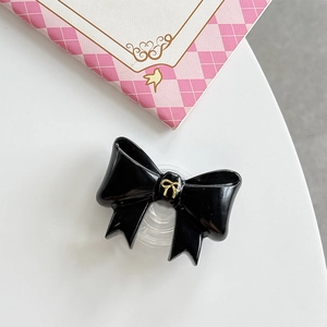 Detail of elegant black glossy bow-shaped expanding phone grip with gold accent on white base