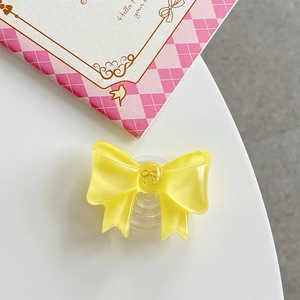 Detail view of a yellow bow-shaped collapsible phone grip with translucent resin finish