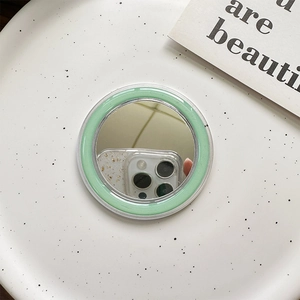 Detail of mint green MagSafe mirror phone accessory on a white ceramic tray