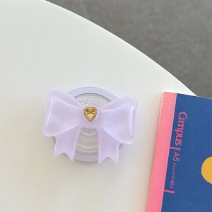 Dettaglio del supporto telefono a fiocco in resina viola con texture a cuore dorato