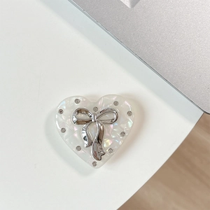 Macro view of rhinestone heart phone holder with silver bow on magnetic surface