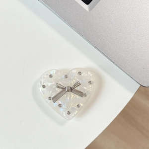 Macro detail of iridescent heart phone grip featuring a silver rhinestone bow decoration