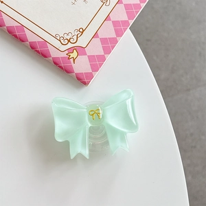 Close-up of a mint green bow phone grip with resin texture and gold butterfly detail