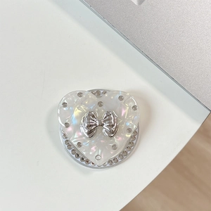 Macro detail of rhinestone heart phone socket with a silver metallic bow and pearl finish